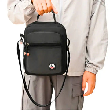 Black crossbody travel bag with adjustable strap, front pocket, and top handle for daily commute or short trips