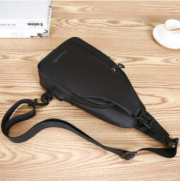 Black sling bag with adjustable strap, ideal for travel and daily use, shown on wooden surface