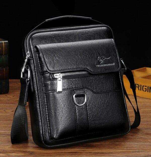 Black leather crossbody laptop bag with zipper pockets on wooden table