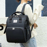 Woman wearing large black backpack with multiple compartments, ideal for school or travel.