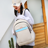 Beige student backpack with blue stripe, worn by woman in white shirt and cap, ideal for school or travel