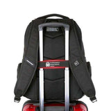 Black travel backpack fitted on top of red rolling suitcase with telescopic handle
