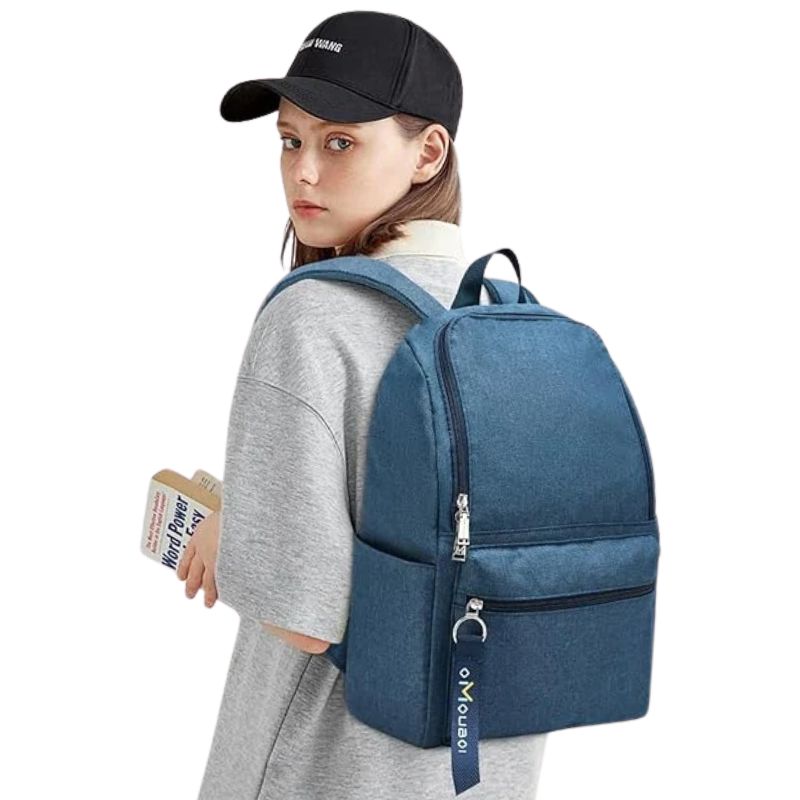 Blue denim-style student backpack with front pocket, worn by teen holding book, ideal for school or travel