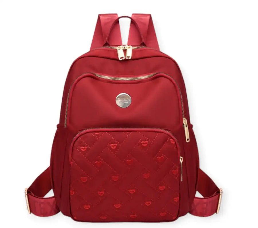 Red quilted heart-pattern backpack with gold zippers, ideal for travel or school use.