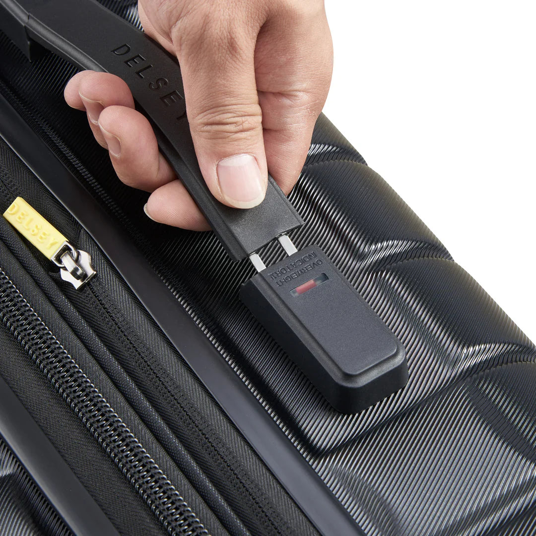 Hand using Delsey luggage scale on black travel suitcase with zipper detail