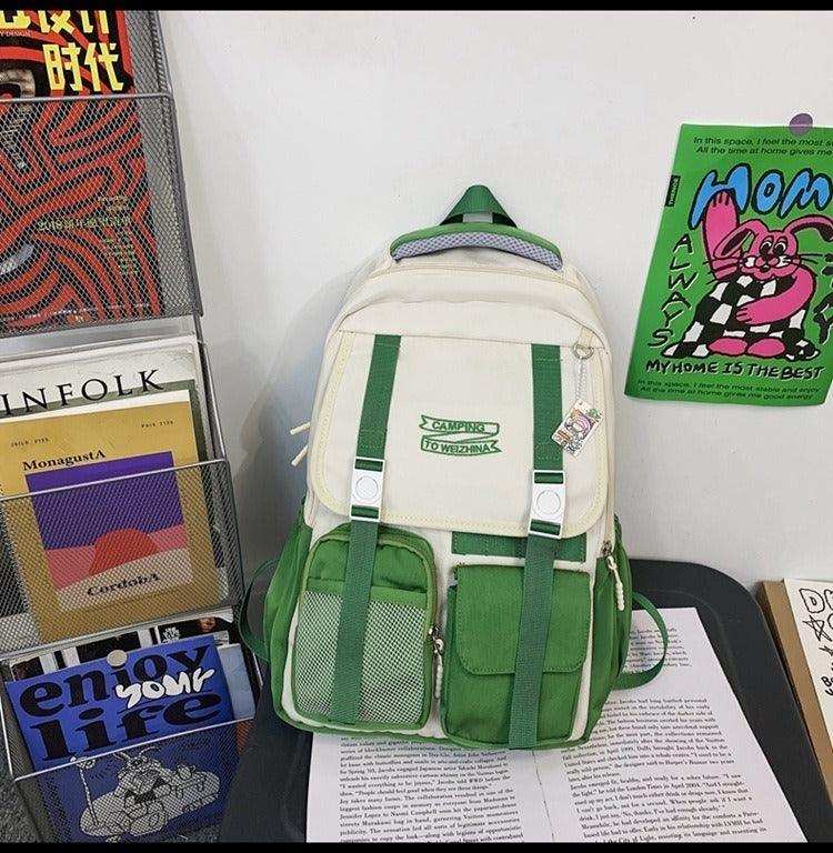 Green and cream student backpack with front pockets, ideal for school or travel, displayed on books.