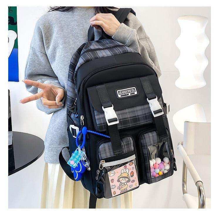 Trendy plaid school backpack with front pockets, cartoon patch, and colorful accessories.