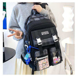 Trendy plaid school backpack with front pockets, cartoon patch, and colorful accessories.
