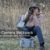 Gray camera backpack & shoulder bag for travel, worn by photographer in outdoor setting