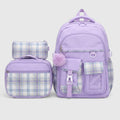 A lavender purple school backpack set with matching lunch bag and pencil case, featuring plaid pattern panels and a fuzzy pom-pom accent, shown on a light gray background.