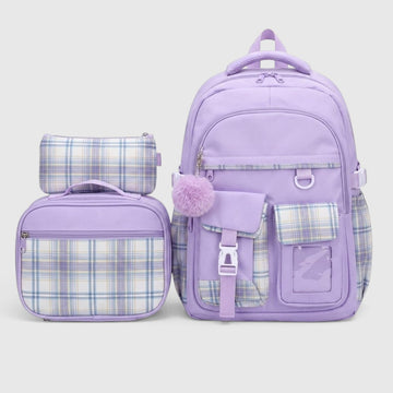 A lavender purple school backpack set with matching lunch bag and pencil case, featuring plaid pattern panels and a fuzzy pom-pom accent, shown on a light gray background.